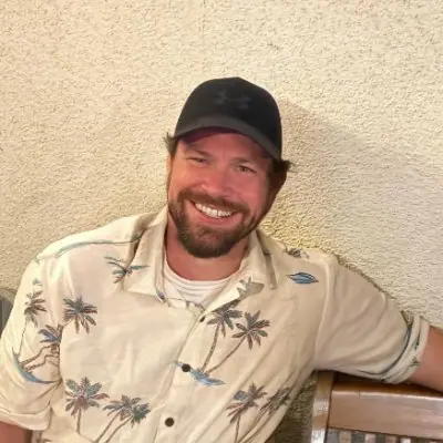 Mike Shute, founder of PaperBagged, smiling in a ball cap and palm-print shirt